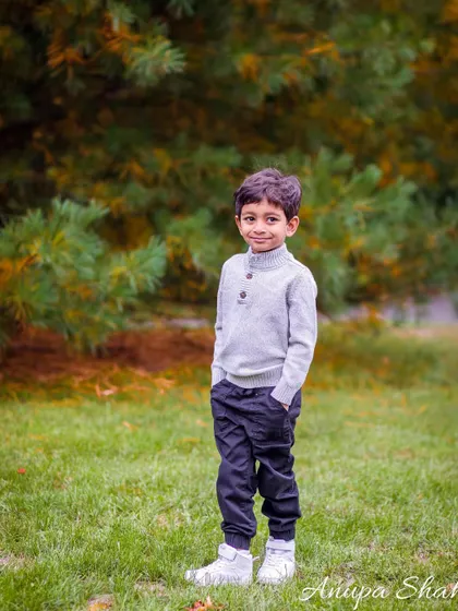 A handsome portrait of a young boy posing confidently in a park. This shot captures his personality and style during a family maternity session.