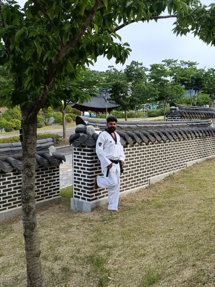 Leaning against a traditional Korean wall, a blend of modern training and ancient culture.