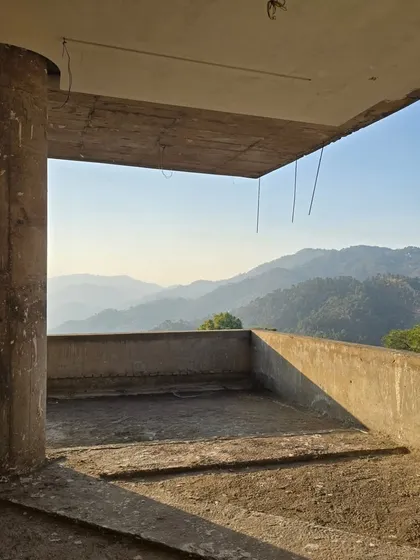 From within the under-construction hillside home, a raw concrete frame perfectly captures the breathtaking panorama of the mountains. This demonstrates how the design prioritizes the view from the very beginning.