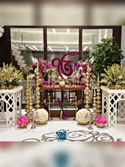 A full view of the main altar for an Anand Karaj. The setup includes the floral Ek Onkar, balanced with large bouquets, traditional floor seating arrangements, and ornate decor elements, all designed to honor the sacred traditions of a Sikh wedding.