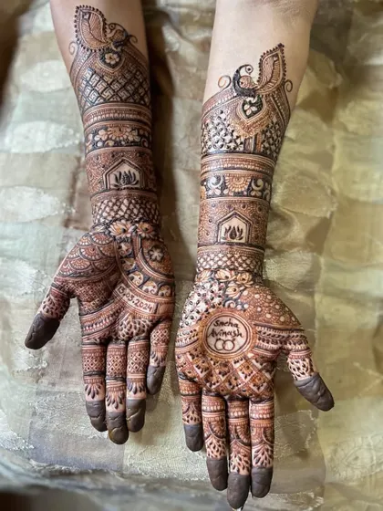 A beautiful engagement mehendi with traditional peacock armlets and circular mandala designs on the palms that include the couple's initials.