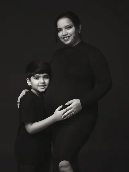 A timeless black and white portrait of a mother and her son. His arm around her, and her hand on her belly, tells a story of love, protection, and new beginnings.