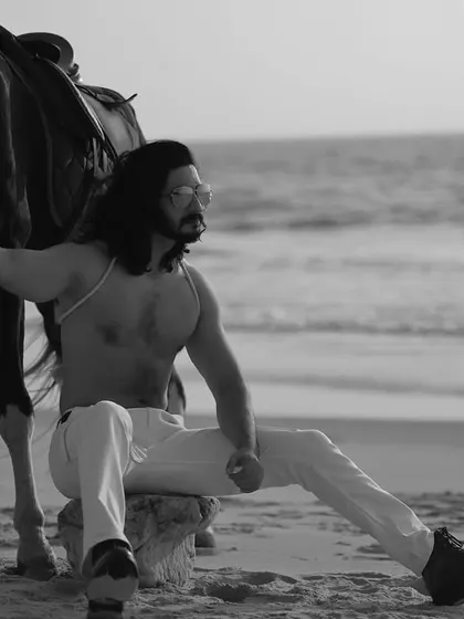 A series of black and white images from a male editorial shoot on the beach with a horse. The monochrome style gives these photos a classic, timeless, and heroic quality.