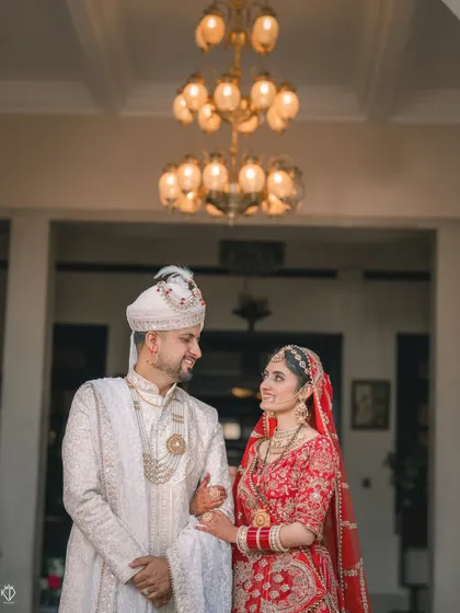 The couple sharing a sweet glance under a grand chandelier, a classic portrait from their wedding day.