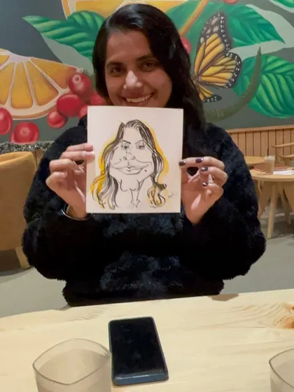 A happy customer at The Black Coffee Cafe, showing off her caricature. A great way to make a cafe visit more memorable.