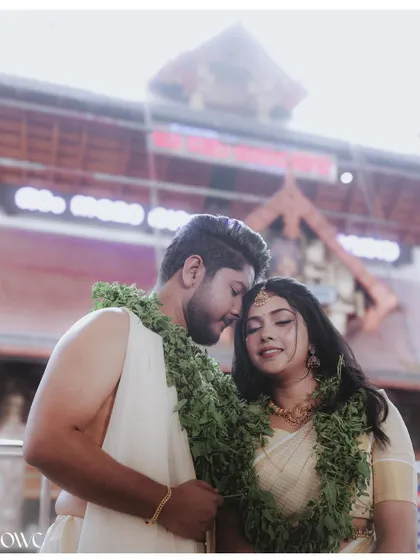 An intimate moment between a newly married couple at a temple, wearing traditional garlands.