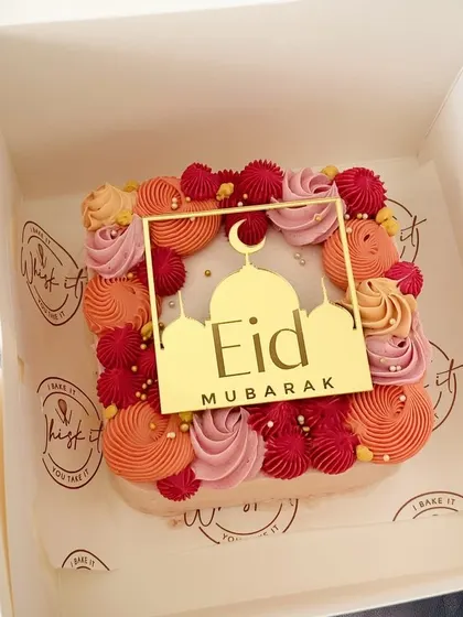 A close-up of the square Eid mini cake, showcasing the vibrant orange, red, and pink piping. It's a joyful cake for a joyful celebration.
