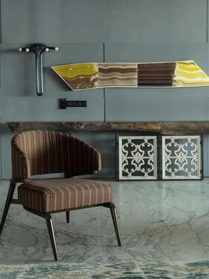 A vignette from the apartment, featured in Elle Decor. This shot highlights the mix of textures and art, including a striped armchair, a stone artwork, and antique marble jali panels.