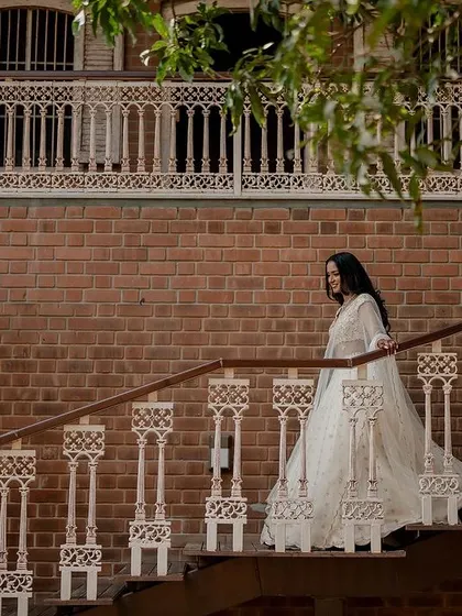 A vision in white. This bride's elegant Tarun Tahiliani lehenga looks absolutely stunning against the rustic brick backdrop, creating a timeless and regal bridal portrait.