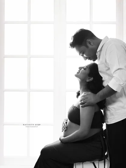 An intimate black and white couple's portrait. The high-contrast window lighting creates a romantic and timeless feel, focusing on their connection.