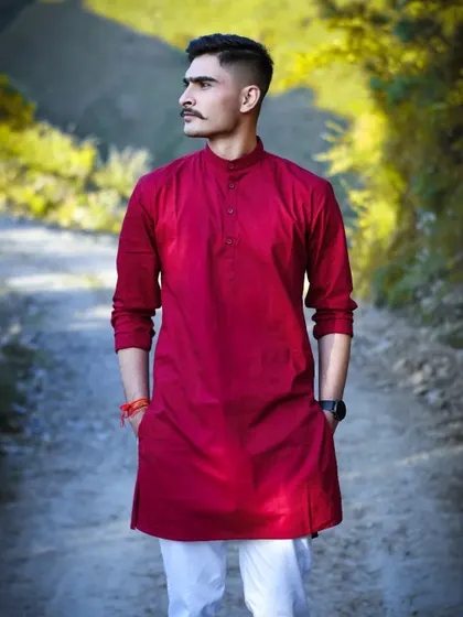 A groom in a simple yet elegant red kurta, pictured on a rustic path. This shows that powerful portraits can be created with casual, traditional wear too.