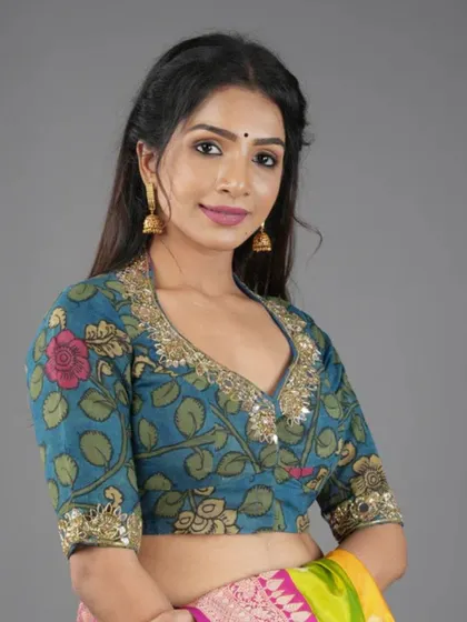 This model wears a floral Kalamkari blouse with gota patti work, paired with simple jhumkas that complement the traditional craft.
