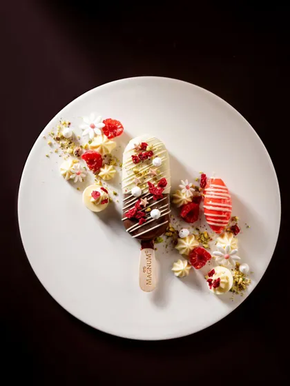 A beautifully plated Magnum bar with a red and white theme, using dehydrated raspberries and white chocolate elements for a sophisticated look.