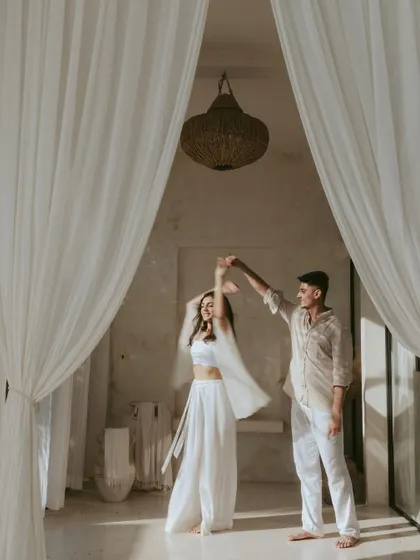 A joyful, candid moment of the couple dancing within the same curtained frame. This shot contrasts beautifully with more static poses, showcasing their dynamic and lively connection during their Bali pre-wedding shoot.