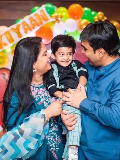 A candid family moment during a jungle-themed second birthday party. The love and happiness are clear as the parents look at their smiling two-year-old.