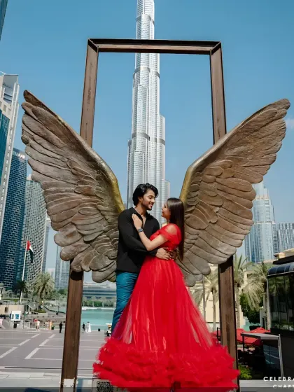 A creative pre-wedding shot in Dubai. The couple poses with an angel wing sculpture, with our red gown adding to the dramatic effect.