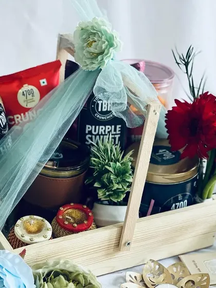 The light green tulle wrapping adds a soft and elegant touch to this abundant pinewood hamper.