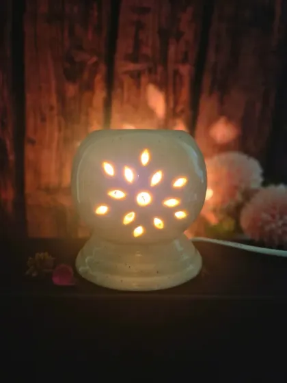 The wax warmer lit in a dark room, showing the beautiful patterns of light it casts. It creates a truly cozy and magical ambiance.