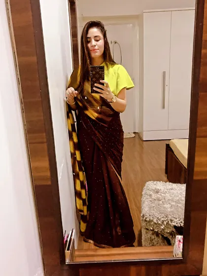 I love mixing colors and styles. Here, a traditional brown and yellow saree is paired with a modern, bright lime-green blouse with flutter sleeves for a unique and eye-catching combination.