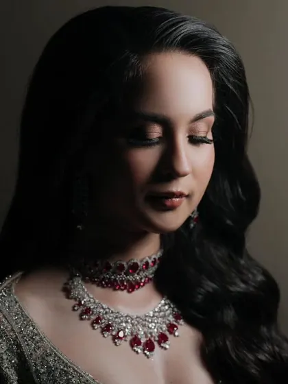 A close-up of the bride's glamorous cocktail night look, featuring a stunning ruby and diamond necklace that perfectly complements her shimmering gown.