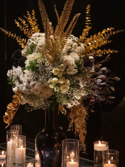 A magnificent centerpiece from the black and gold event, featuring white hydrangeas, black roses, and sprays of gold-painted foliage. This arrangement is a perfect example of our bold and artistic approach to floral design.