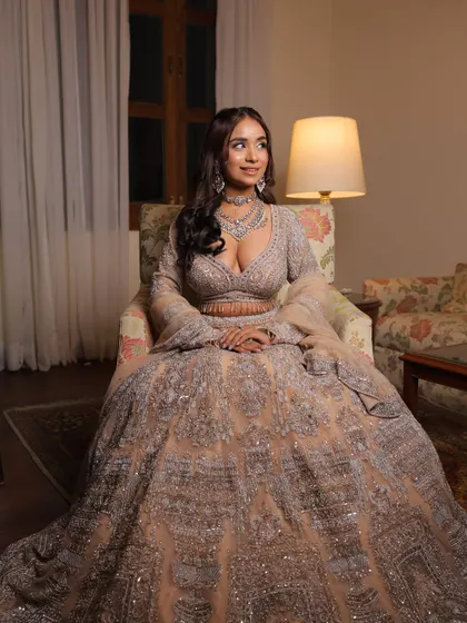 A full-length seated shot of the silver-grey engagement lehenga. The voluminous skirt and detailed embroidery create a look of pure elegance.