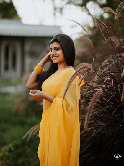 A lovely portrait of the bride in a simple yellow saree, her smile radiant in the natural outdoor light.