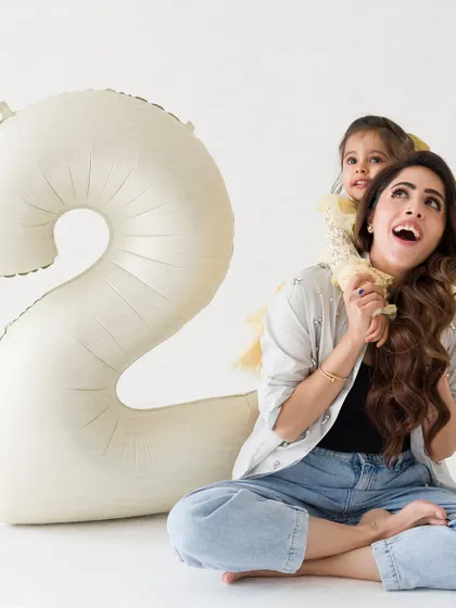 A sweet and candid moment from a second birthday shoot. The little girl gets a piggyback ride from her mom, both sharing a happy, upward gaze.