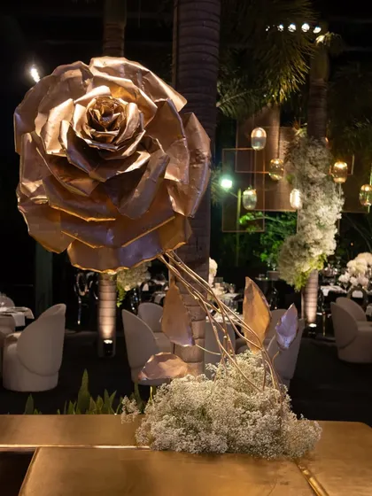 A giant, sculptural rose made of gold metal serves as a dramatic decor piece. This is an example of the custom art installations I can create to make your event unique.