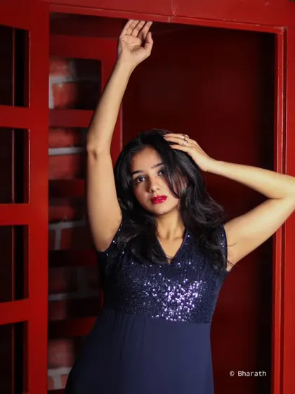 A dynamic pose against a textured red studio backdrop. The color adds energy and drama to the photograph.