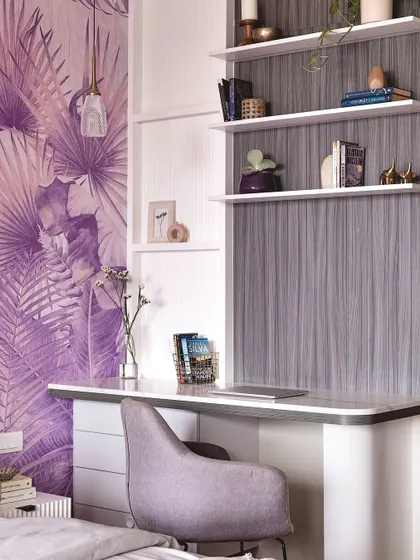 A bold and glamorous study nook, featuring a stunning purple tropical wallpaper. The white desk with curved edges and open shelving creates a workspace that is both functional and full of personality.