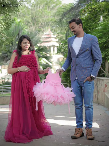 A glimpse of the future. The couple holds up a tiny, adorable pink dress, sweetly announcing they are expecting a baby girl.