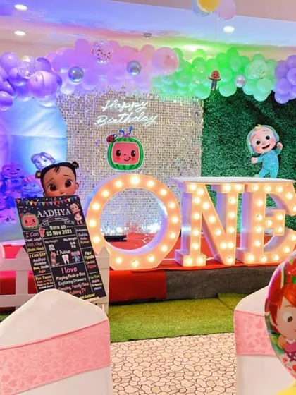 A Cocomelon-themed first birthday with a unique backdrop combining a sequin wall and a green foliage wall.