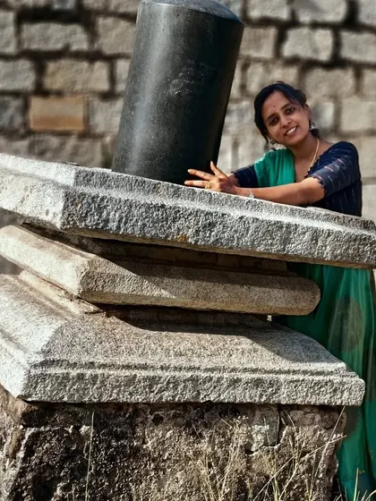 Posing with a broken but beautiful Shivalingam at a heritage site.