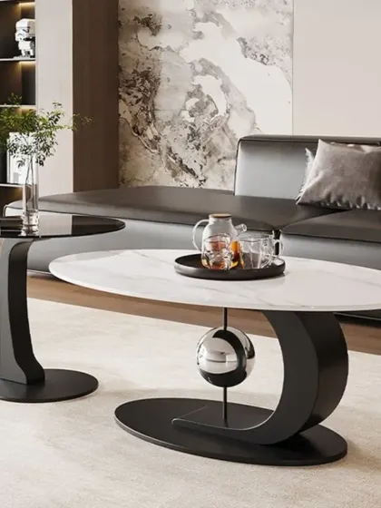 A modern nesting center table set. The main table has a white marble top with a sculptural black base, while the smaller side table features a black glass top.
