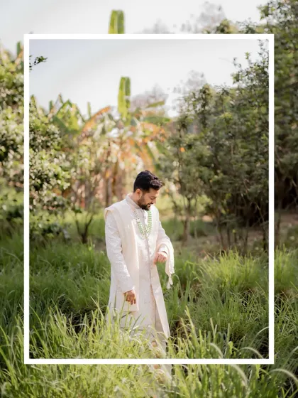 A candid shot of the groom checking his watch while standing in a beautiful, natural setting.