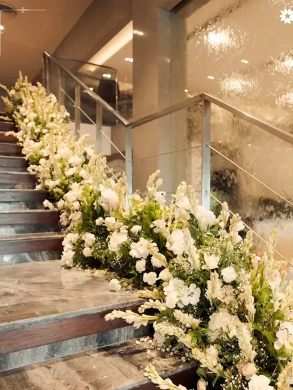 A cascade of white flowers adorning the main staircase. We use florals to beautify not just the main event areas but the transitional spaces as well, ensuring a beautiful experience from the moment guests arrive.