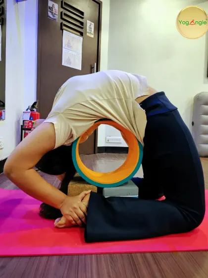 A student gracefully flows into a deep backbend using the yoga wheel. This prop is instrumental in our Wheel Yoga sessions for opening the heart, enhancing flexibility, and finding balance.