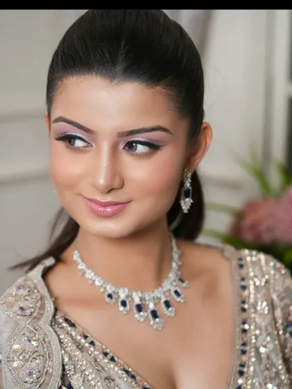 A close-up of a model wearing a diamond and sapphire necklace that perfectly matches her silver and blue lehenga.