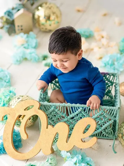 A playful moment in a macrame basket. This shot captures the baby's happy expression and the beautiful textures of the teal and gold setup.