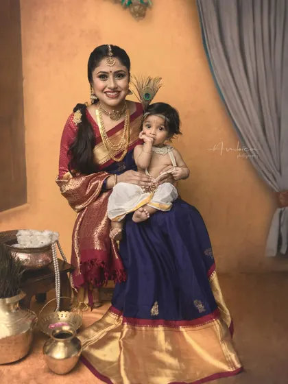 A tender moment between mother and son. The baby, dressed as Krishna, gently touches his mother's face in this beautiful, emotional portrait.