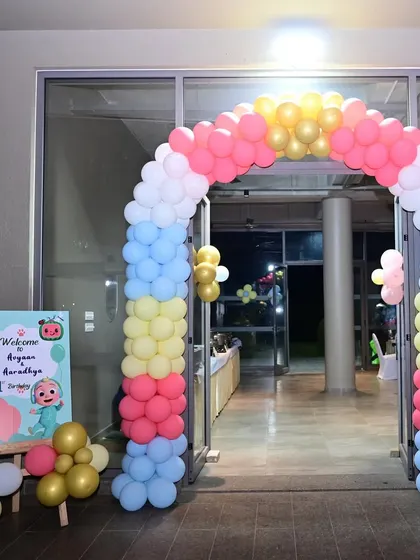 This Cocomelon-themed entrance uses a pastel color palette for a softer look. The balloon arch frames the doorway, and a welcome sign with characters from the show greets the guests.