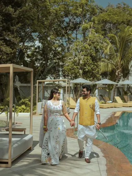 A stylish portrait of a couple walking by the pool in beautiful ethnic wear. This is a perfect example of a candid-style portrait that still feels elegant and well-composed.