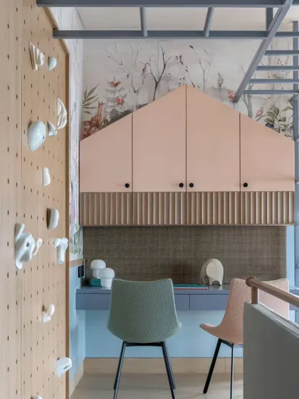 This clever design incorporates a study area and storage above, accessible by a ladder that is part of a larger monkey bar structure. The house-shaped cabinet adds a whimsical touch to the functional space.