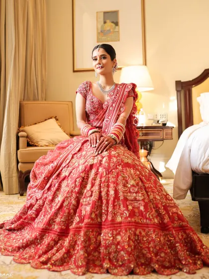 A full-length portrait of the bride in her magnificent red Rahul Mishra lehenga. The makeup is classic and elegant, perfect for a grand wedding at the Taj Mahal Palace.