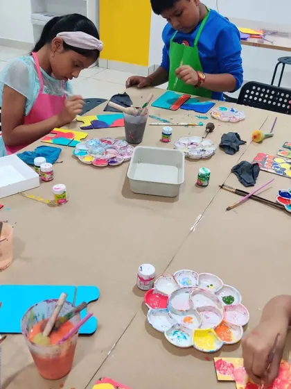 A busy table at an art party where kids are painting and creating their own personalized desk calendars.
