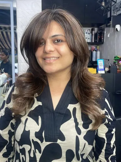 A beautiful layered cut with face-framing bangs, styled into soft, bouncy curls.