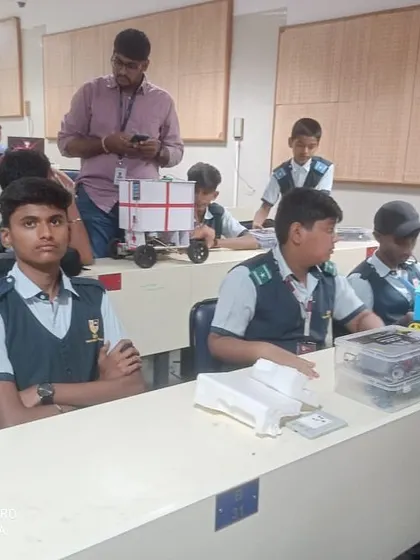 Teams of students sit with their completed robot projects, awaiting judging and the start of the competition rounds.