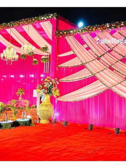 A vibrant outdoor setup with bright pink draping. The elegant patterns created with the fabric and the small water features make for a festive and lively atmosphere.