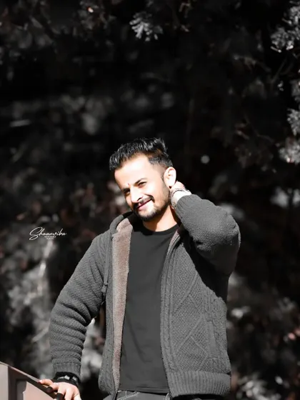 A candid, smiling portrait with a dark, moody background. The contrast makes the subject's expression the main focus of the image.